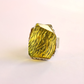 amber ring with a textured design on a light pink background