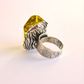 Silver amber ring with a zebra-patterned band and yellow gemstone on a light background