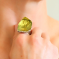 Close-up of a amber ring with a green stone on a blurred background