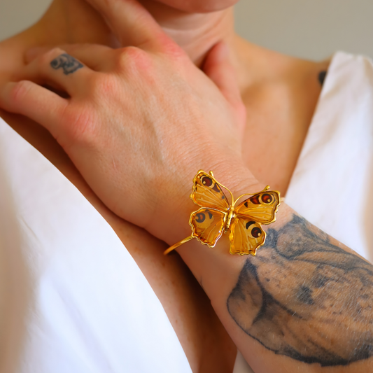 Gold butterfly amber bracelet on a wrist with tattoos