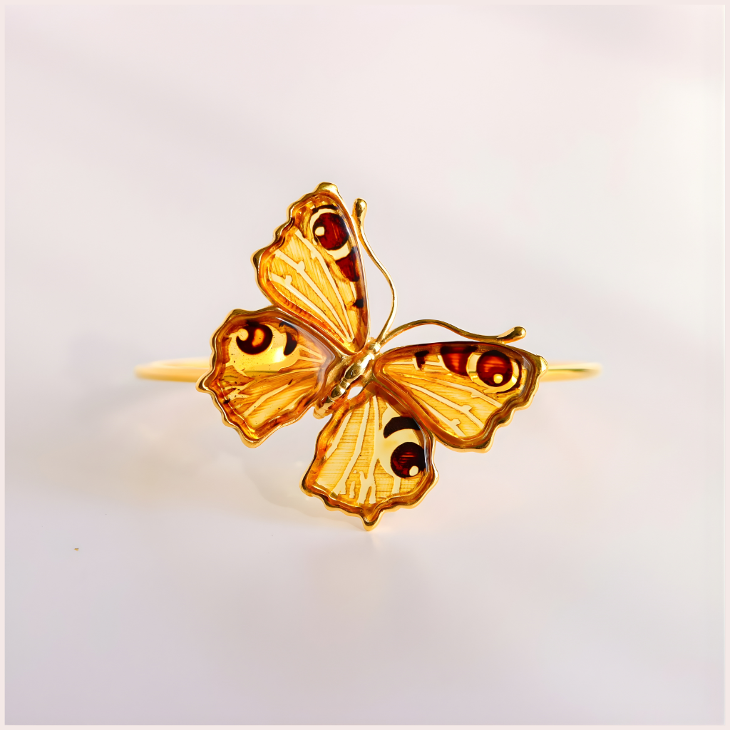 Gold butterfly amber bracelet on a light gray background