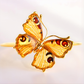 Gold butterfly amber bracelet with amber-colored wings on a white background