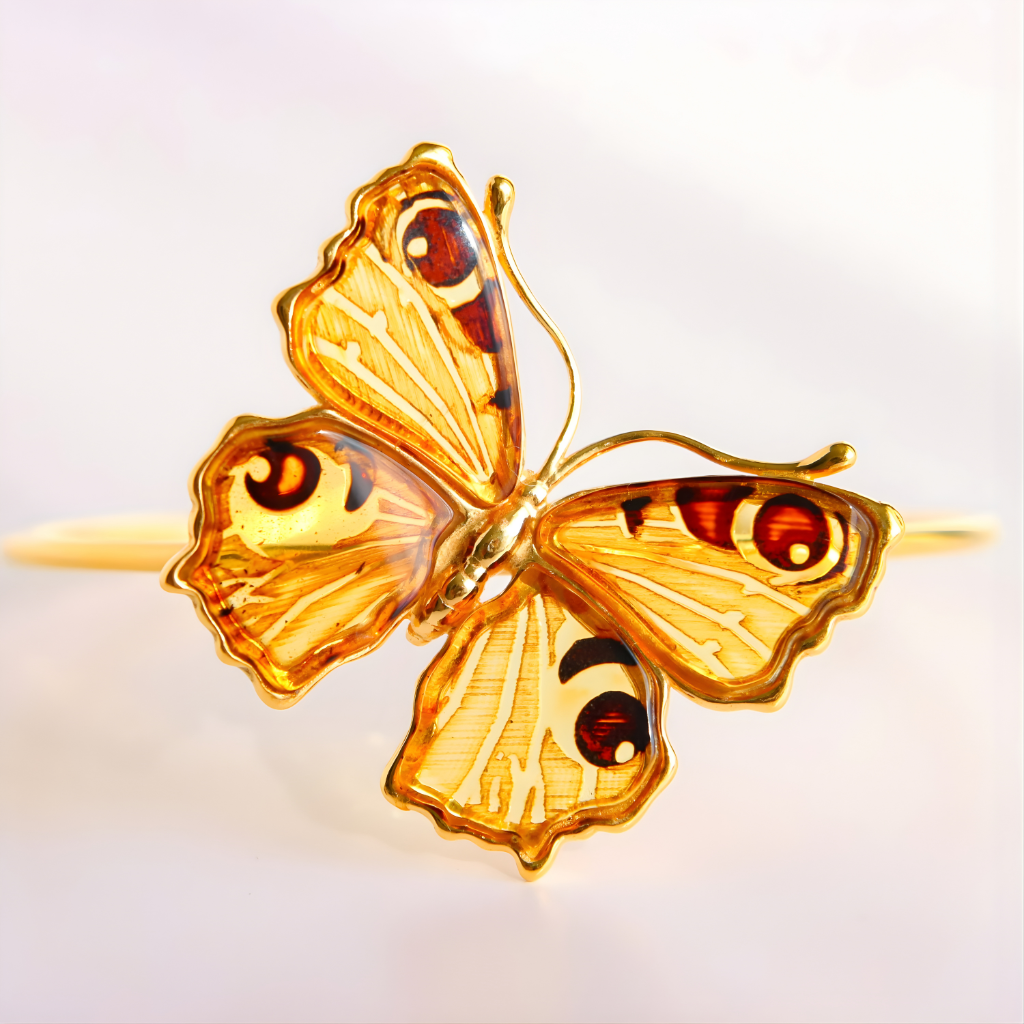 Gold butterfly amber bracelet with amber-colored wings on a white background