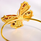 Gold butterfly amber bracelet with intricate design on a white background