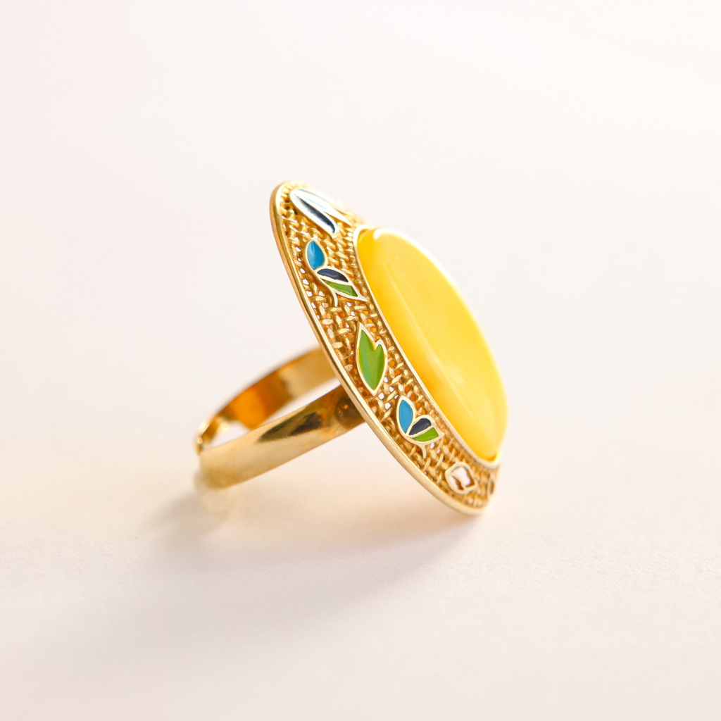 Gold butterscotch amber ring with a yellow center and green and blue accents on a light background
