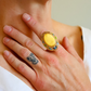 Close-up of a hand wearing a butterscotch amber ring with a decorative band.