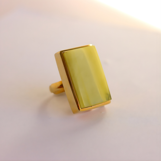 Gold amber statement ring with a rectangular stone on a light background
