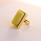 Gold amber statement ring with a square stone on a light pink background