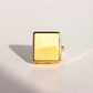 Gold square-shaped amber ring on a light gray background
