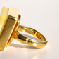 Gold amber ring with a rectangular design on a light gray background