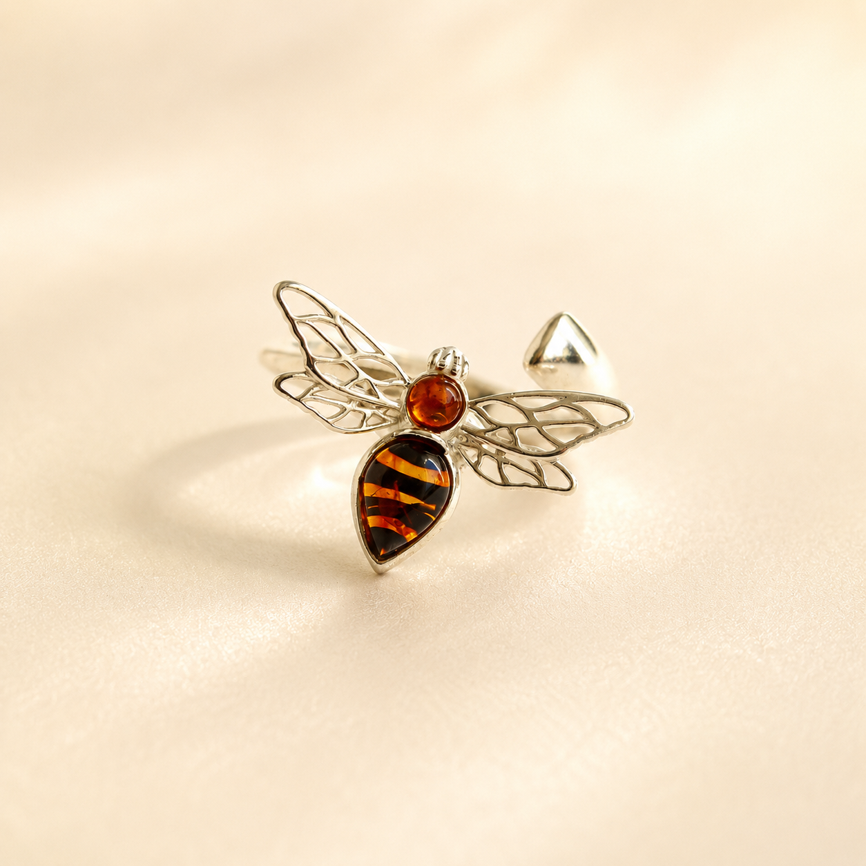 bee ring with silver wings and striped gemstone on light beige background