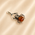 Amber Spider Pendant with a orange gemstone on light beige background
