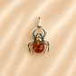 amber spider pendant with an orange gemstone silver legs and black eyes on beige pink background

