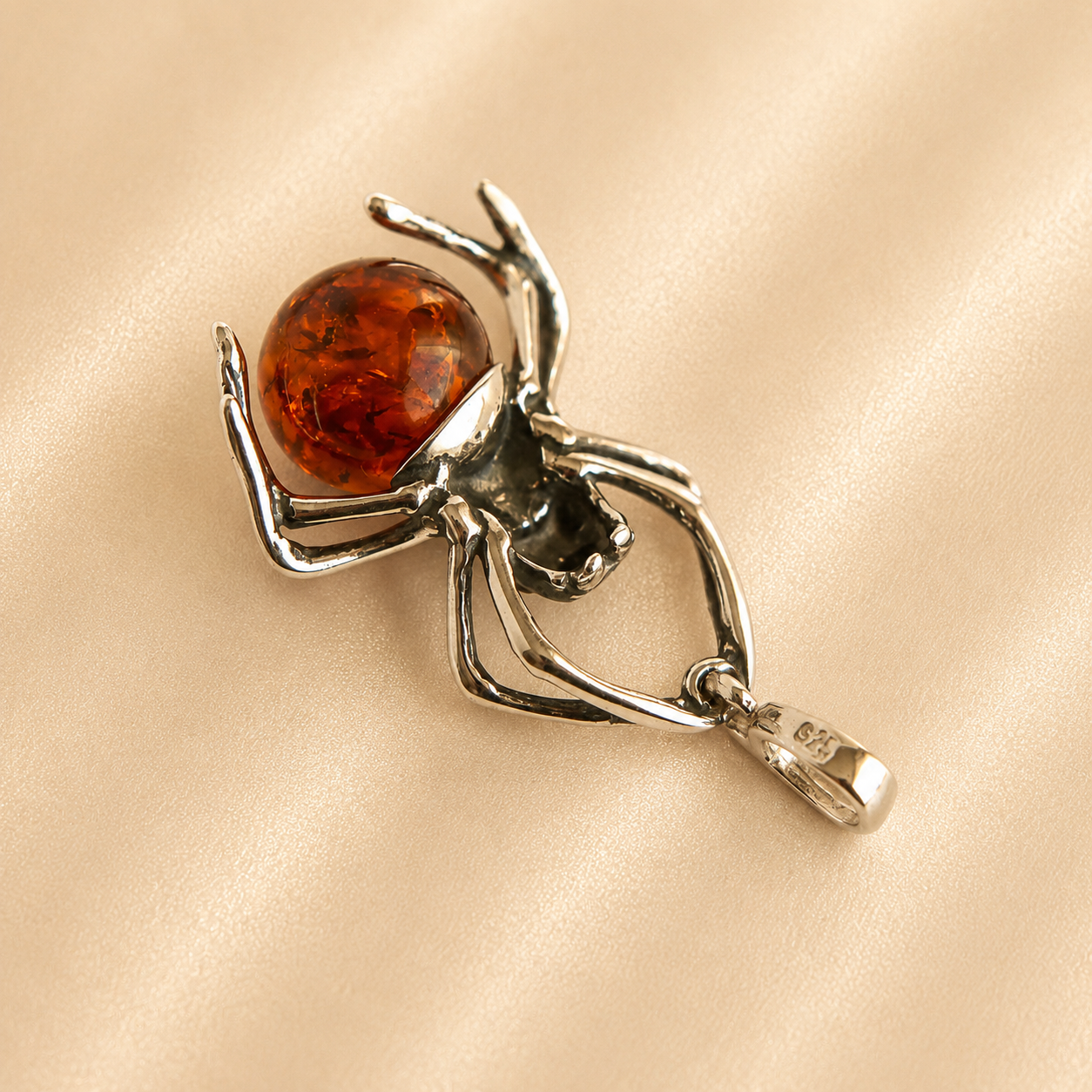 amber spider pendant with brown gemstone on beige background