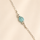 raven skull Necklace with a blue bead on a beige background