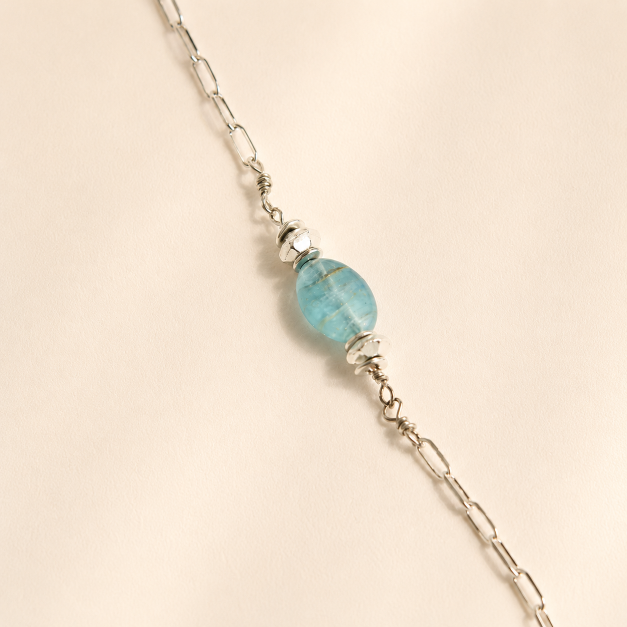 raven skull Necklace with a blue bead on a beige background