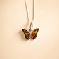 Butterfly Necklace against a beige background