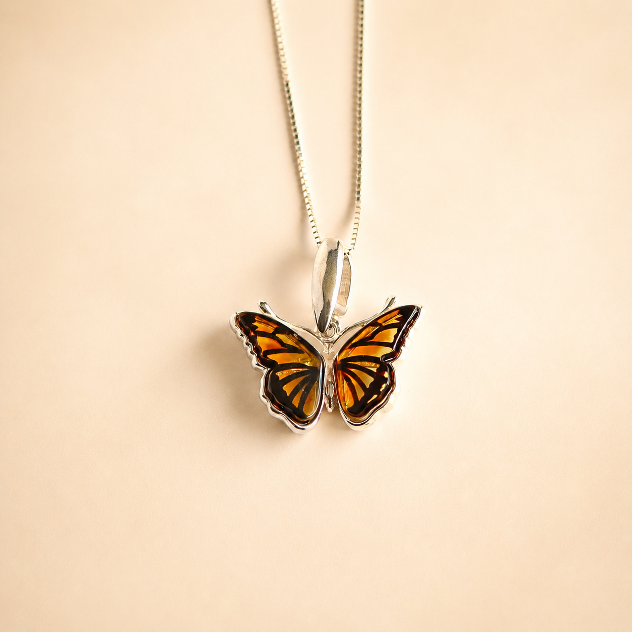 Butterfly Necklace against a beige background