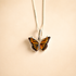 Butterfly Necklace against a beige background