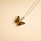 Butterfly necklace against a beige background