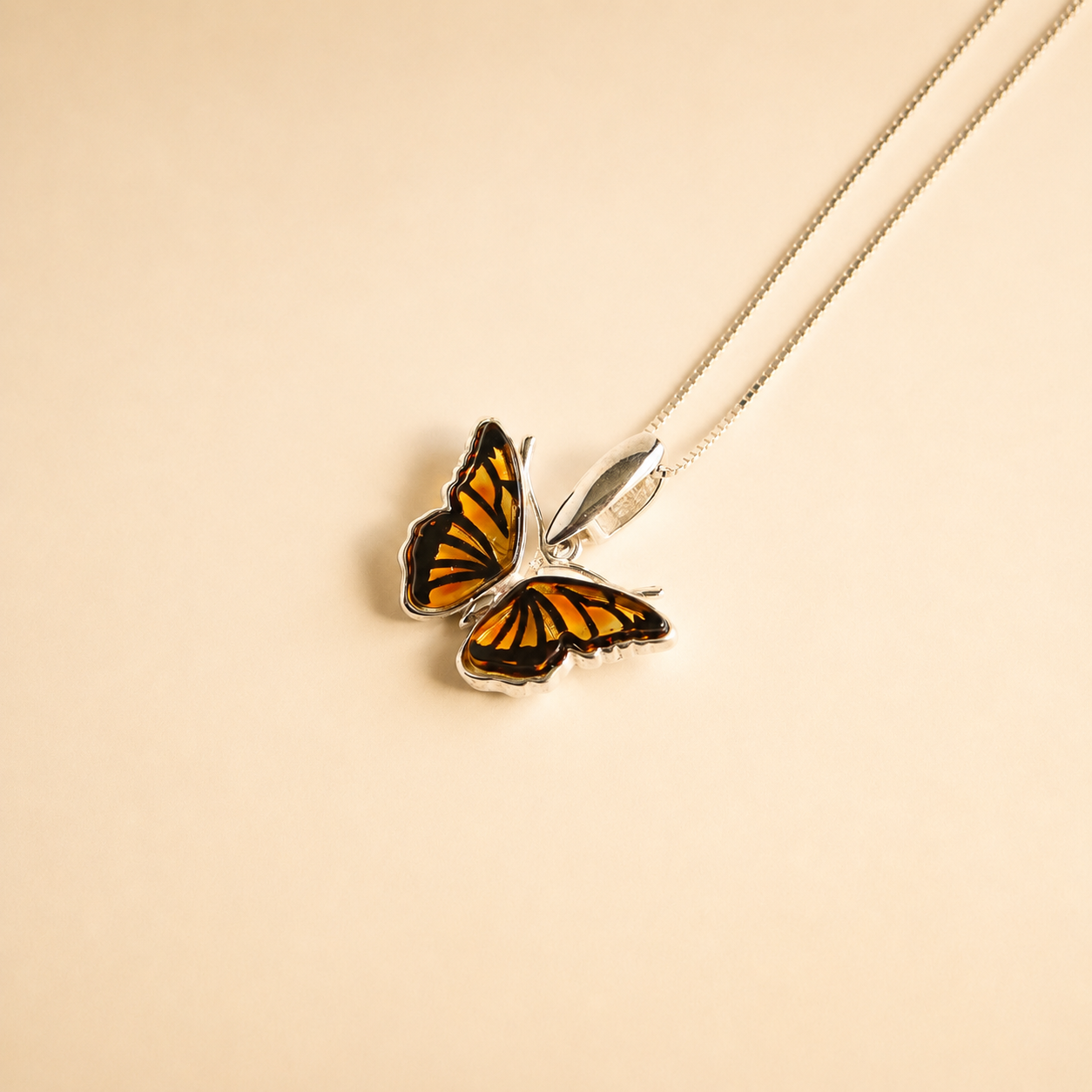 Butterfly necklace against a beige background