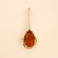 Gold amber necklace pendant with a large amber stone on a beige background
