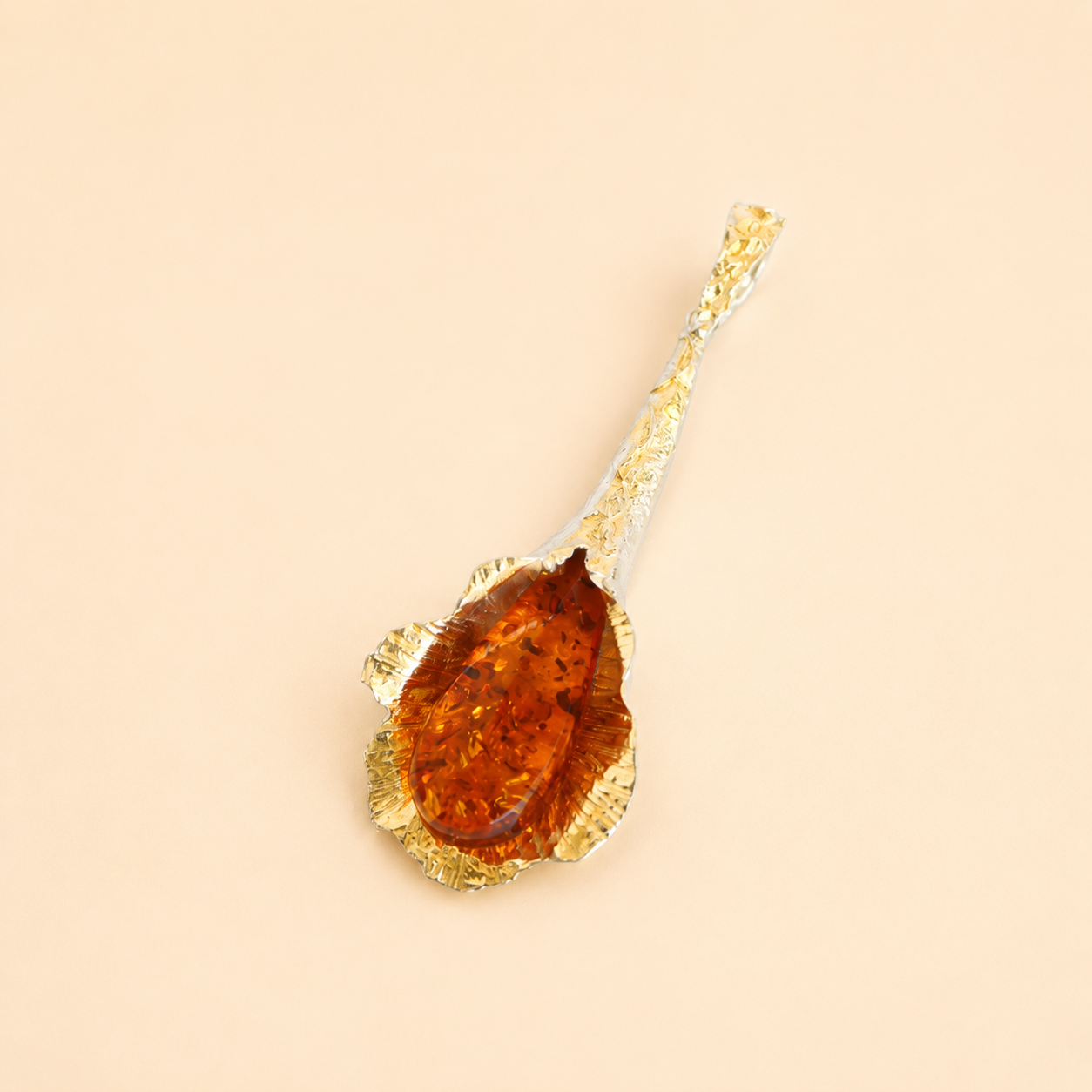 Gold amber necklace pendant with a large amber stone on a beige background