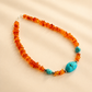 beaded Necklace with orange beads and turquoise accents on a beige background