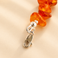 Close-up of amber beaded necklace with a silver clasp on a beige background