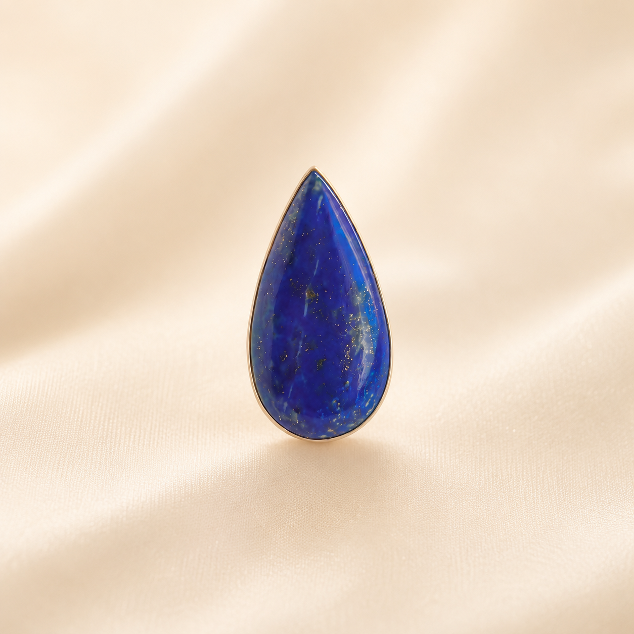 Teardrop-shaped lapis lazuli ring on a beige background