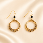 Gold hoop earrings with beads on a beige background