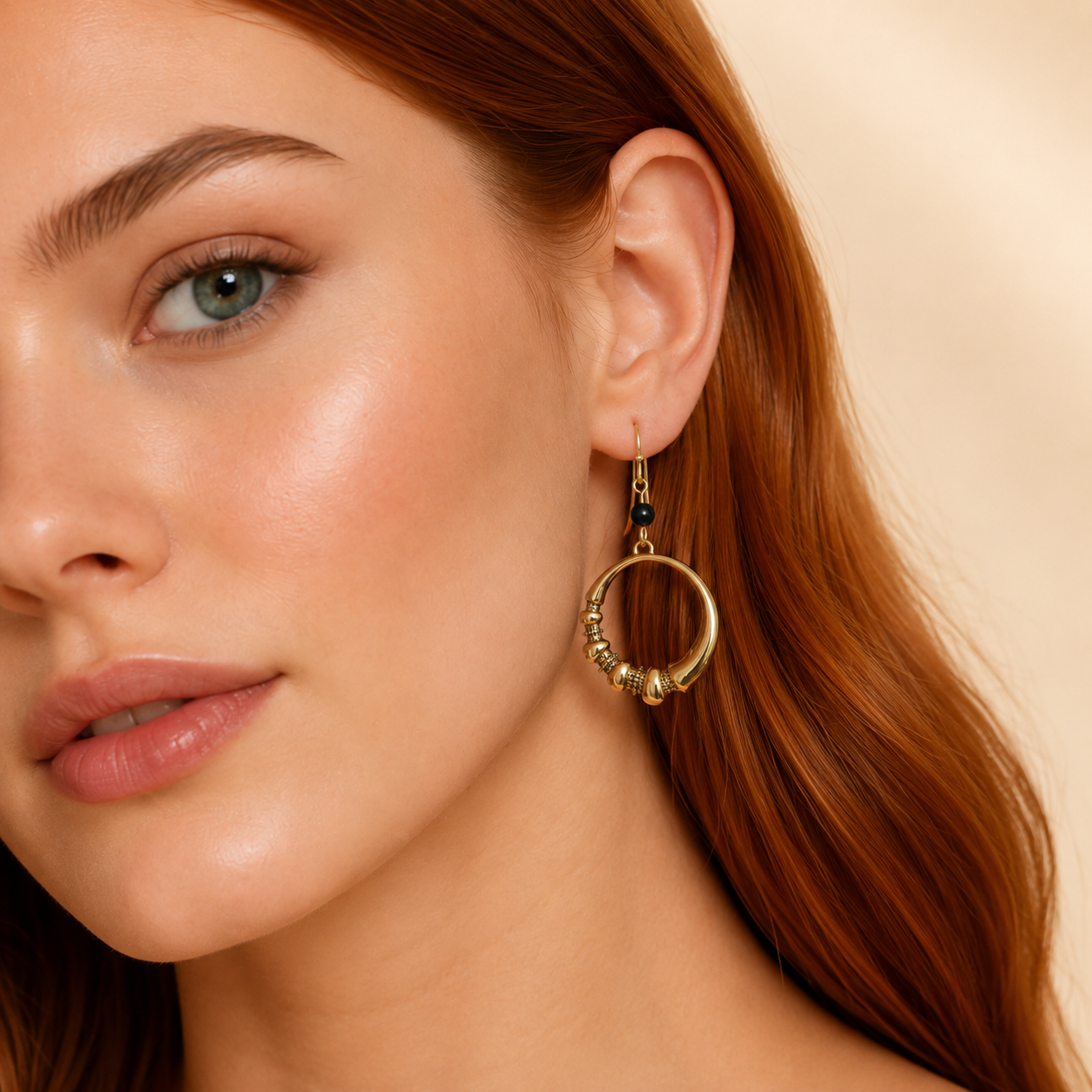 Close-up of a woman wearing gold hoop earrings with a neutral background