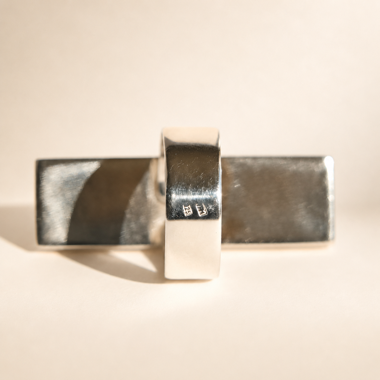 Silver amber ring with a textured surface on a beige background