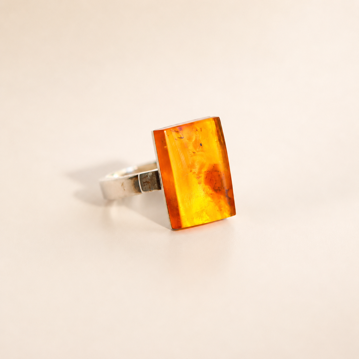 Rectangular Amber ring in silver on white cream background