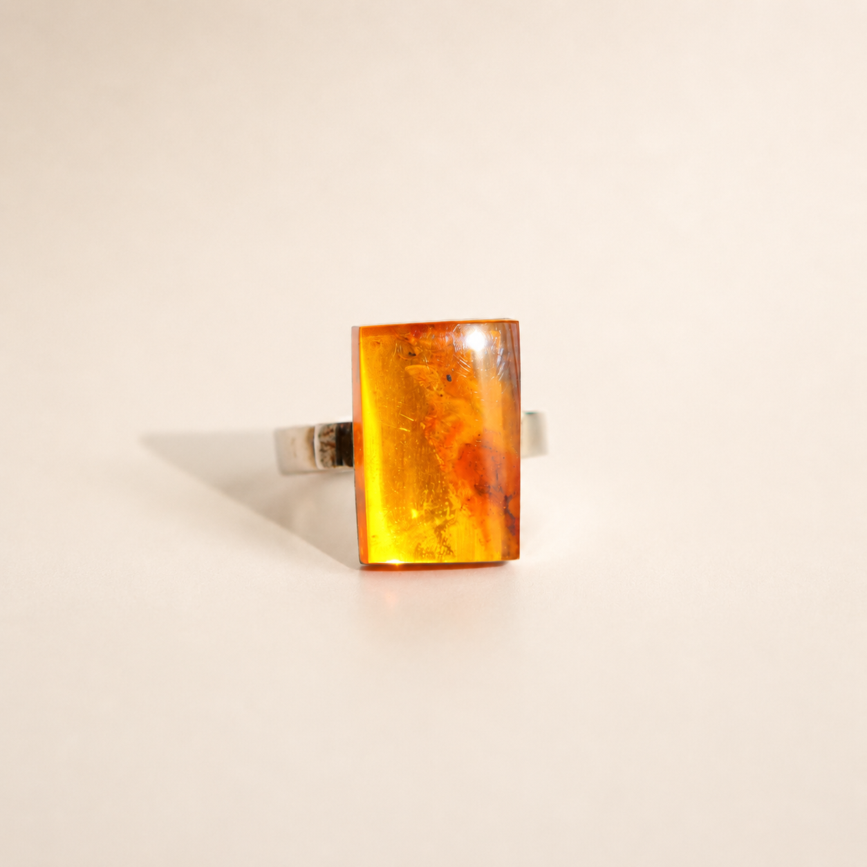 rectangular amber ring with orange gemstone on cream background