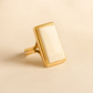Gold white amber ring with a rectangular stone on a beige background
