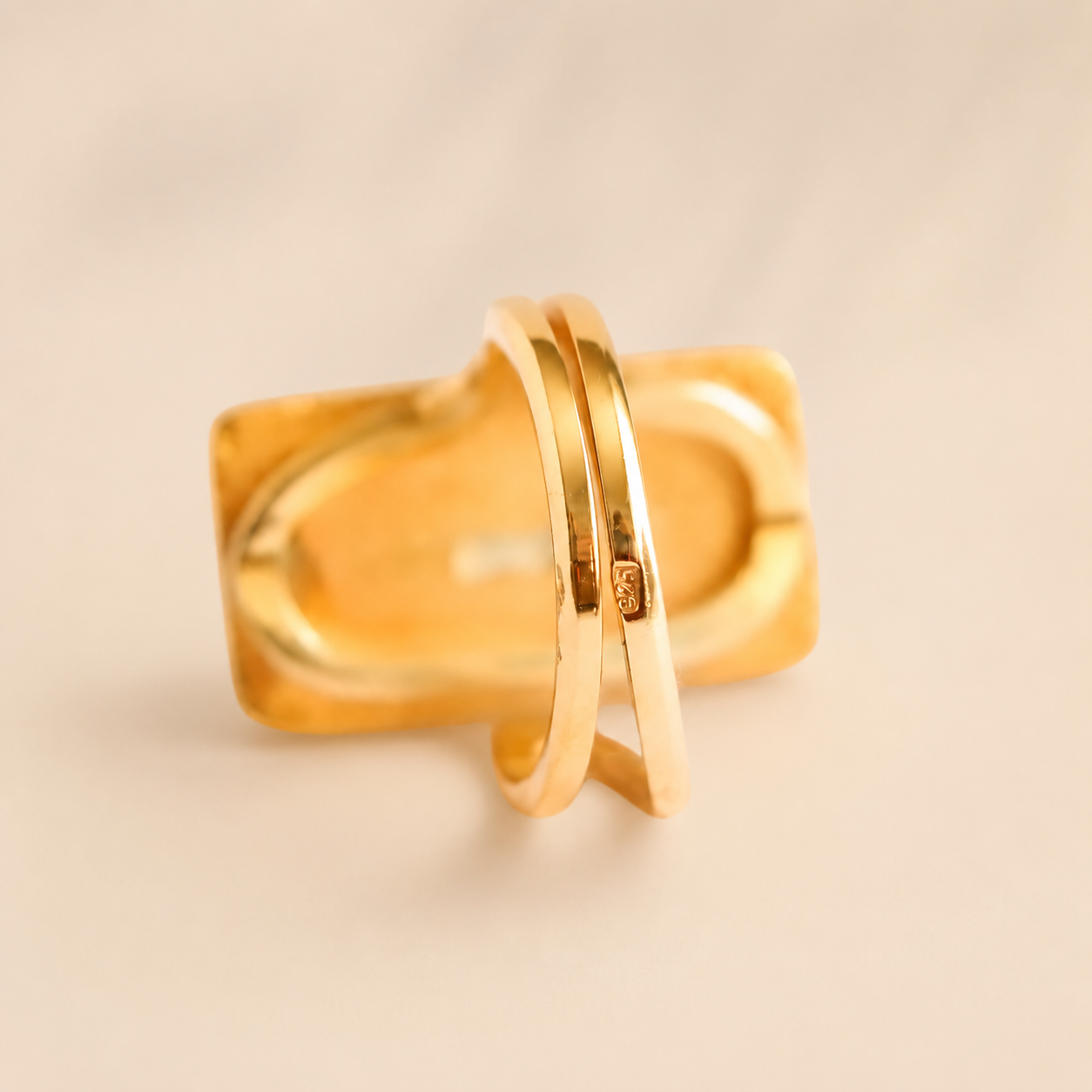 Gold amber ring with a textured band on a beige background