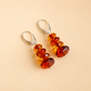 Pair of amber-colored beaded drop earrings on a beige background