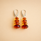 Pair of amber bead drop earrings on a beige background