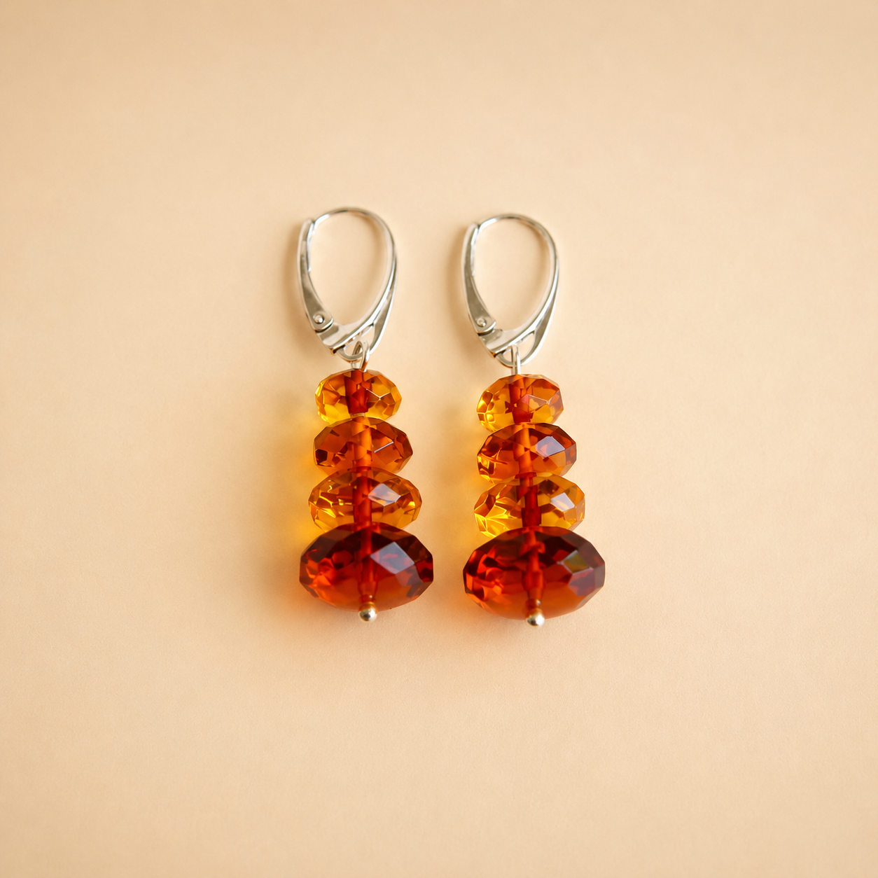 Pair of amber bead drop earrings on a beige background