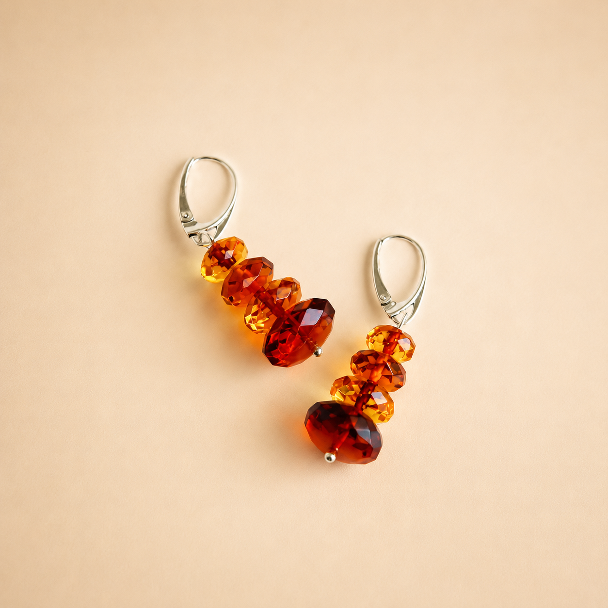 Pair of amber bead drop earrings on a beige background