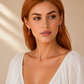 Woman wearing orange amber drop earrings against a beige background