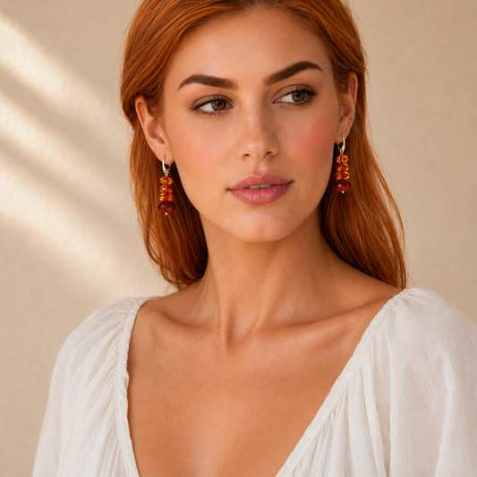 Woman wearing orange amber drop earrings against a beige background