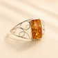 Silver amber cuff bracelet with a rectangular amber stone on a beige background