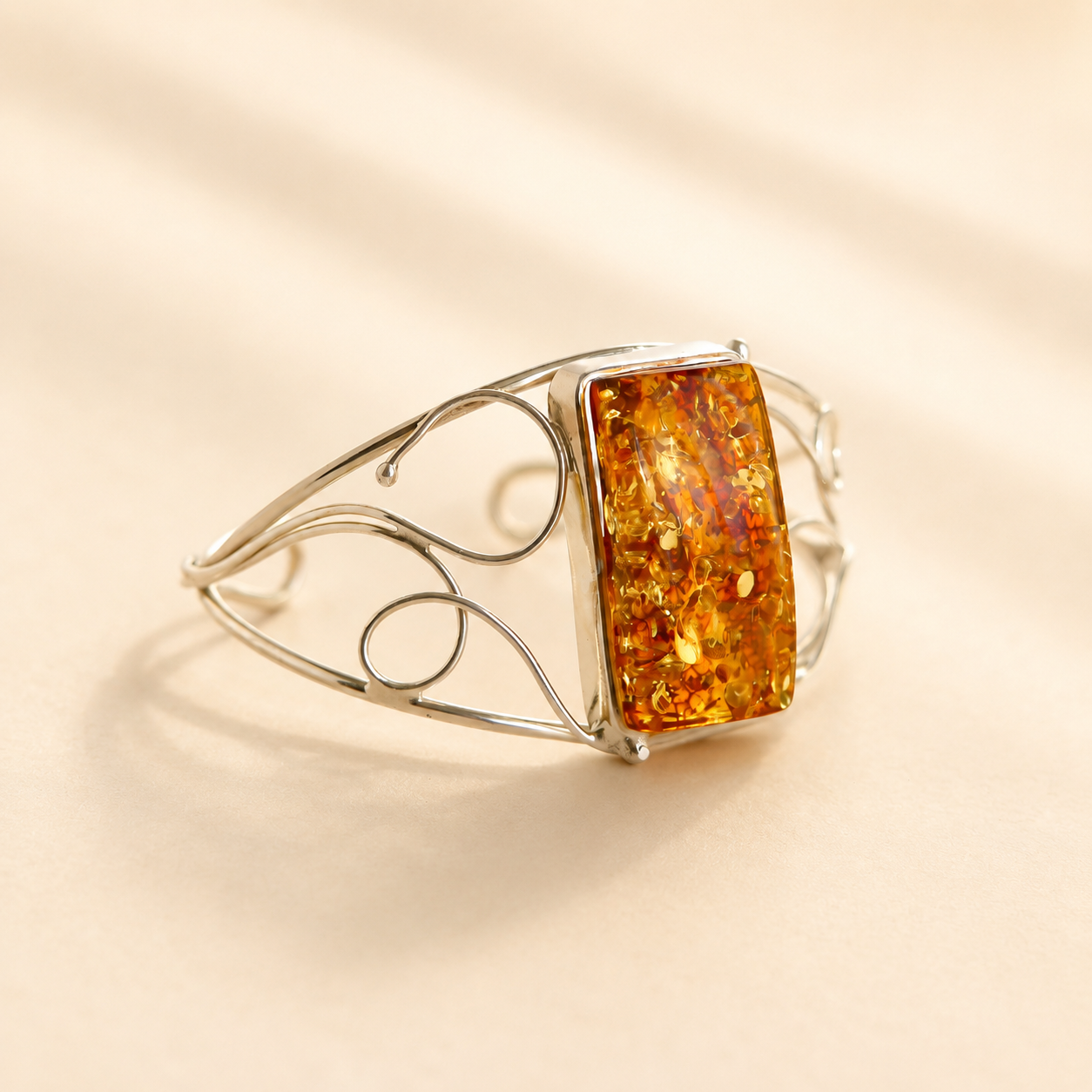 Silver amber cuff bracelet with a rectangular amber stone on a beige background