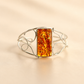 Silver amber cuff bracelet with a rectangular amber stone on a beige background