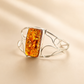 Silver amber cuff bracelet with a rectangular amber stone on a beige background