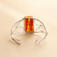 Silver bracelet with amber-colored stone on a beige background