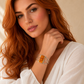 Woman wearing a silver  amber cuff bracelet with an orange gemstone against a neutral background