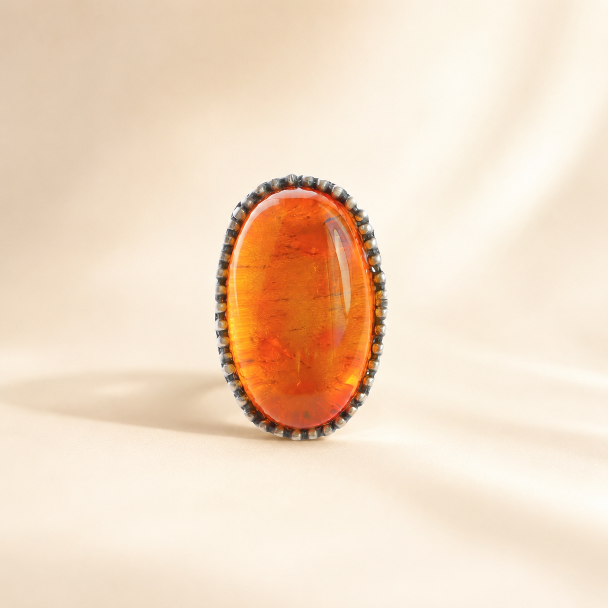 Medieval Statement Ring with a large amber stone on a beige background